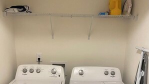 A laundry room with two front-loading Whirlpool washers and a shelf above containing a yellow bottle, a white shoe, and a small box. - New Charming 3-bedroom/2.5 bathroom house in Metro Atlanta area (Decatur)