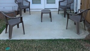 A patio with four chairs and a small table, a white door with a glass panel, and a wall-mounted light fixture. - New Charming 3-bedroom/2.5 bathroom house in Metro Atlanta area (Decatur)