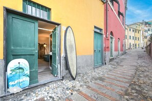 A narrow cobblestone street with buildings on either side, a door with a surfboard, and a sign with the number 27. - Apartment 'Pieds Dans L'eau' with Private Terrace and Wi-Fi (Bogliasco)