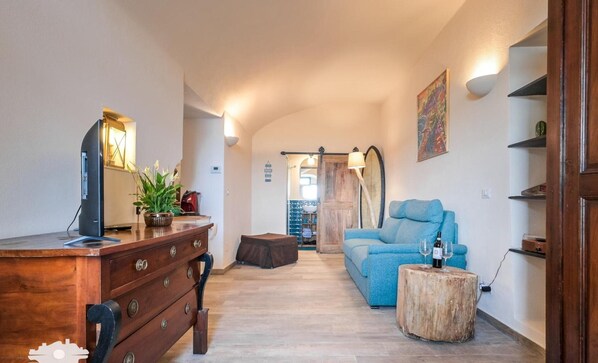 A cozy living room with a wooden dresser, a blue sofa, a wooden coffee table, and a large window.