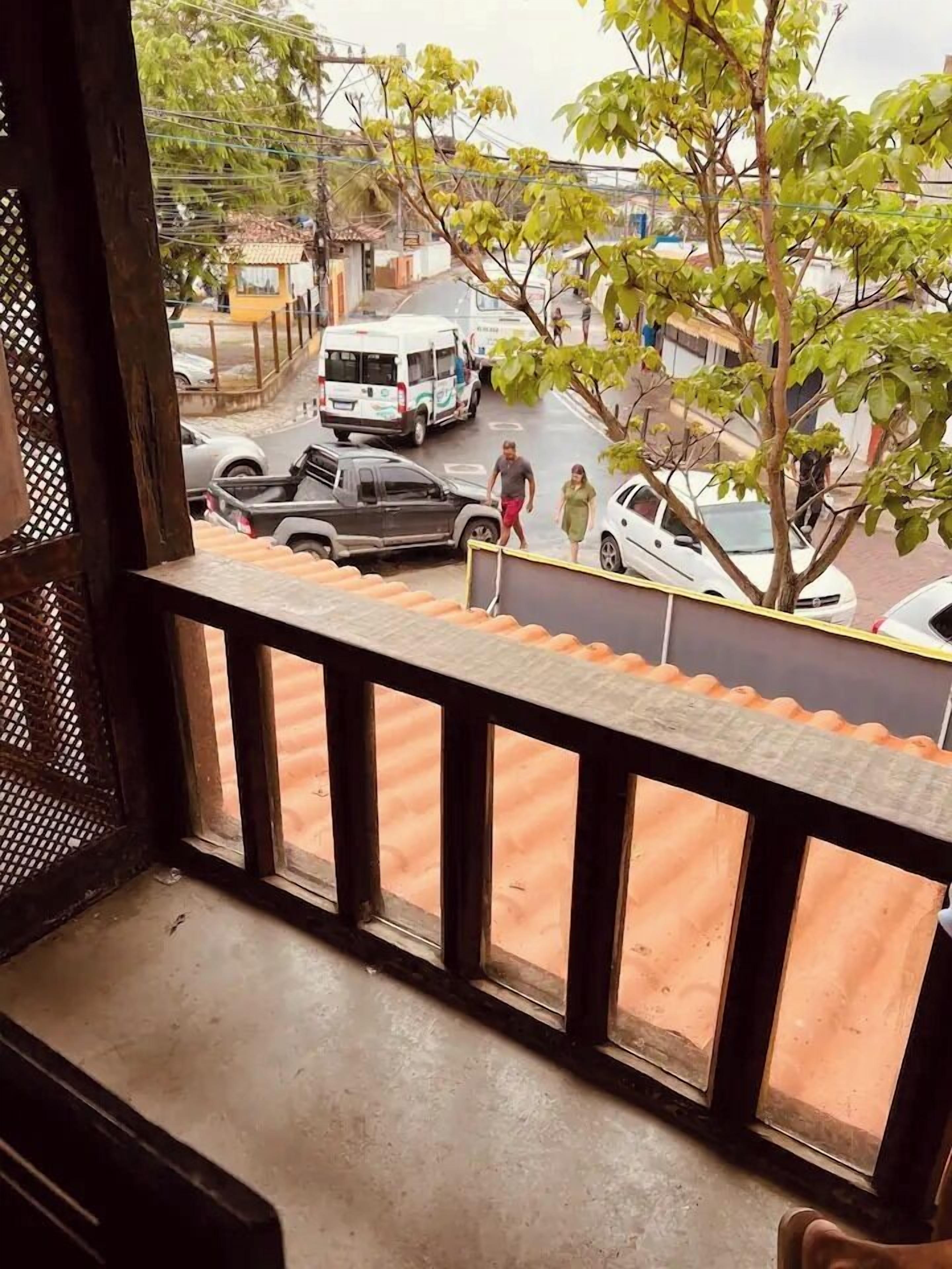 Un balcón con vistas a la calle, un coche aparcado y un edificio al fondo.