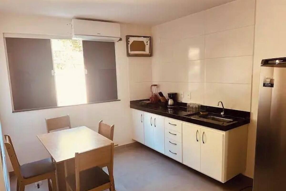 A compact kitchen with a dining table, chairs, a built-in oven, and a refrigerator.