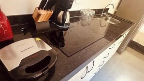 Eine Küche mit Kaffeemaschine, einem Schneidebrett und Gläsern auf der Arbeitsfläche.
