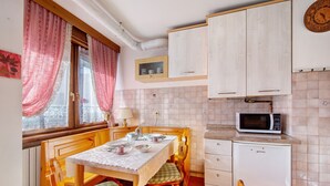 Una cocina con una mesa de comedor, sillas, un microondas y armarios.