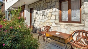 Un edificio de piedra con balcón, muebles de mimbre y una mesa.