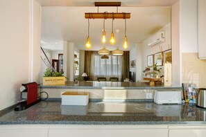 A modern kitchen with granite countertops, a coffee machine, a toaster, and pendant lighting.