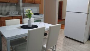 A kitchen with white cabinets, a white refrigerator, a white stove, and a dining table with white chairs. - The Town-Suite at Wanskuck NEW 2-BR APT  Parking (Povidence)