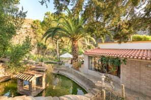 A traditional building with a tiled roof, a stone bridge, and a small pond.