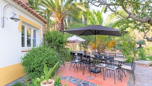 Une terrasse avec des meubles d’extérieur, une table et un parasol.