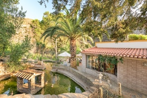 A traditional building with a tiled roof, a stone bridge, and a small pond.