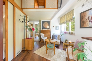A spacious living room with a high ceiling, wooden flooring, a round table, and a comfortable sofa.