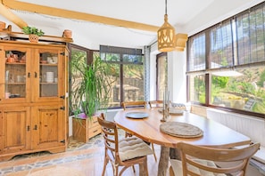 A dining area with a wooden table, chairs, and a hanging light fixture.