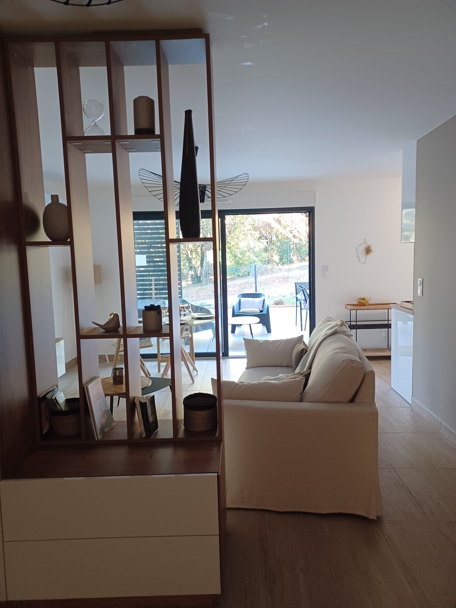 A modern living room with a sofa, a dining area with a table and chairs, and a kitchen area.