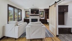 A spacious living room with a fireplace, a large TV, and built-in shelving.