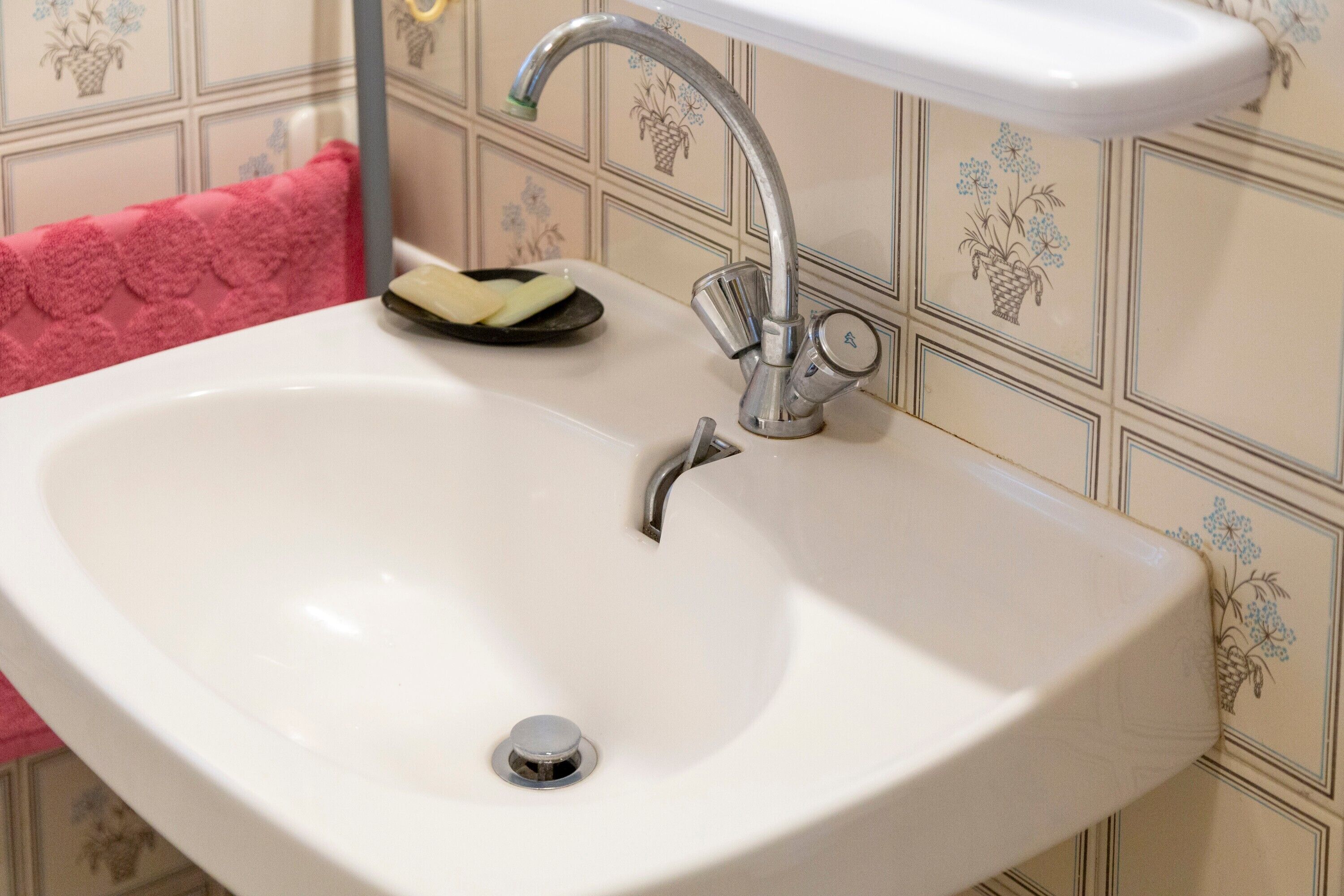 A white sink with a chrome faucet and a soap dish.