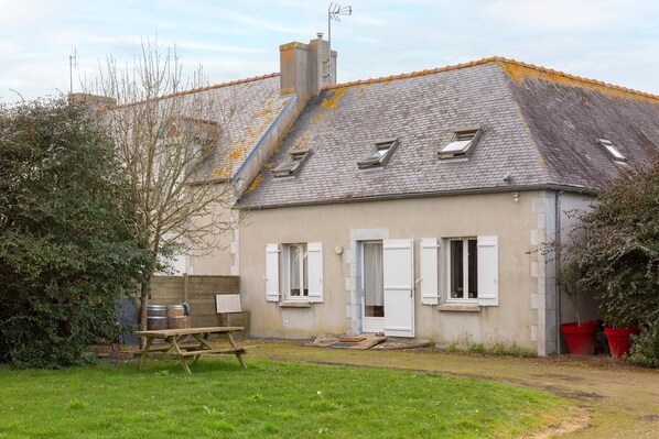 A house with a sloped roof, a chimney, and a small garden with a picnic table.