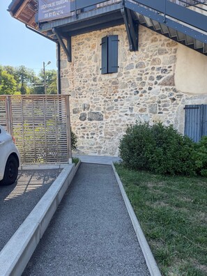 A stone building with a wooden fence, a gravel pathway, and a car parked in front.