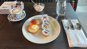 A table with a plate of food, a cup of coffee, a glass of water, and condiments. - IL Corridore - Locanda Bistrò (Medesano)
