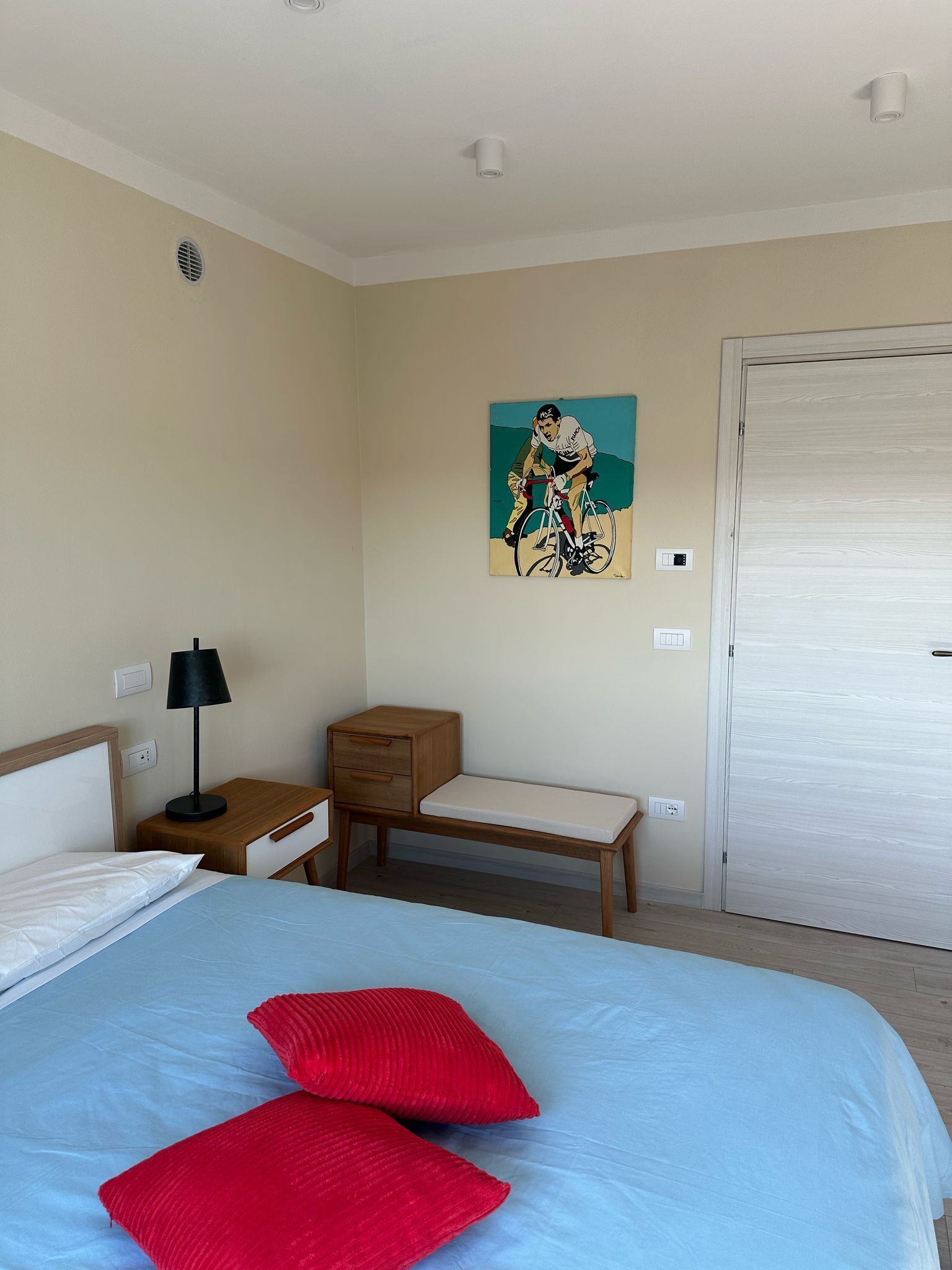 Una habitación de hotel con una cama, una mesita de noche, un escritorio, una silla y una puerta.