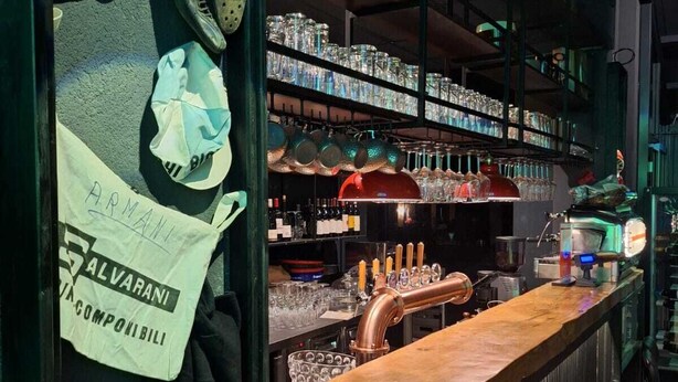 A bar area with a copper tap, shelves of glassware, and a sign for 'Salvarani'. - IL Corridore - Locanda Bistrò (Medesano)
