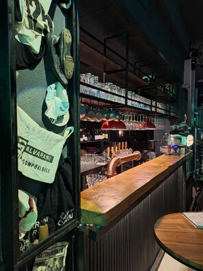 A bar area with a copper tap, shelves of glassware, and a sign for 'Salvarani'. - IL Corridore - Locanda Bistrò (Medesano)