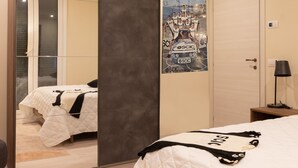 A bedroom with a bed, a mirror, a poster, a door, and a nightstand. - IL Corridore - Locanda Bistrò (Medesano)