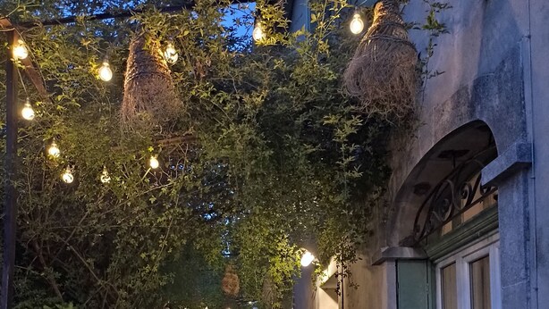Un espace extérieur aménagé avec des murs en pierre, une cheminée rustique et des guirlandes lumineuses.