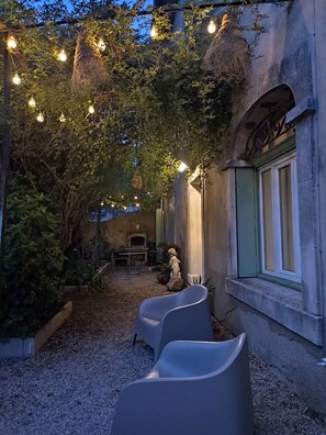 An outdoor seating area with stone walls, a rustic fireplace, and string lights.