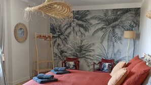 Une chambre avec un grand lit, une échelle en bois, une fresque murale et un luminaire suspendu.