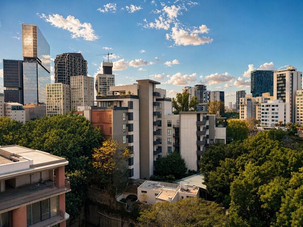 Un paysage urbain avec des bâtiments modernes, dont un gratte-ciel remarquable entièrement vitré et un bâtiment doté d’une façade géométrique originale.
