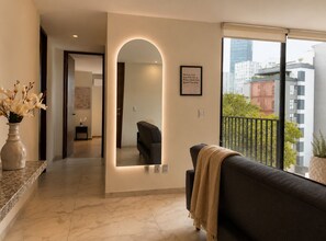 A modern living room with a sofa, a mirror, and a vase of flowers.
