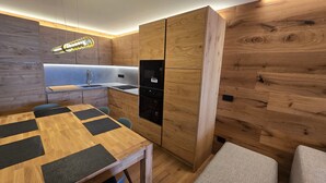 Une cuisine compacte dotée d’un four à micro-ondes encastré, d’un évier et d’un revêtement mural en bois.