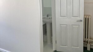 A white door leading to a bathroom with a sink and a toilet.