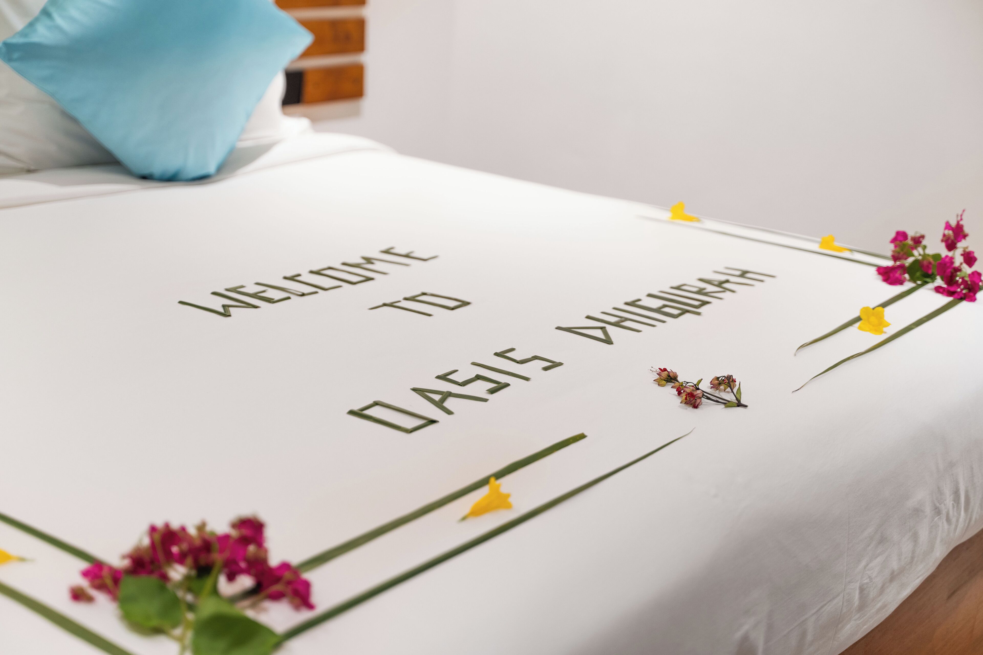 Een bed met een welkomstbericht en decoratieve bloemen.