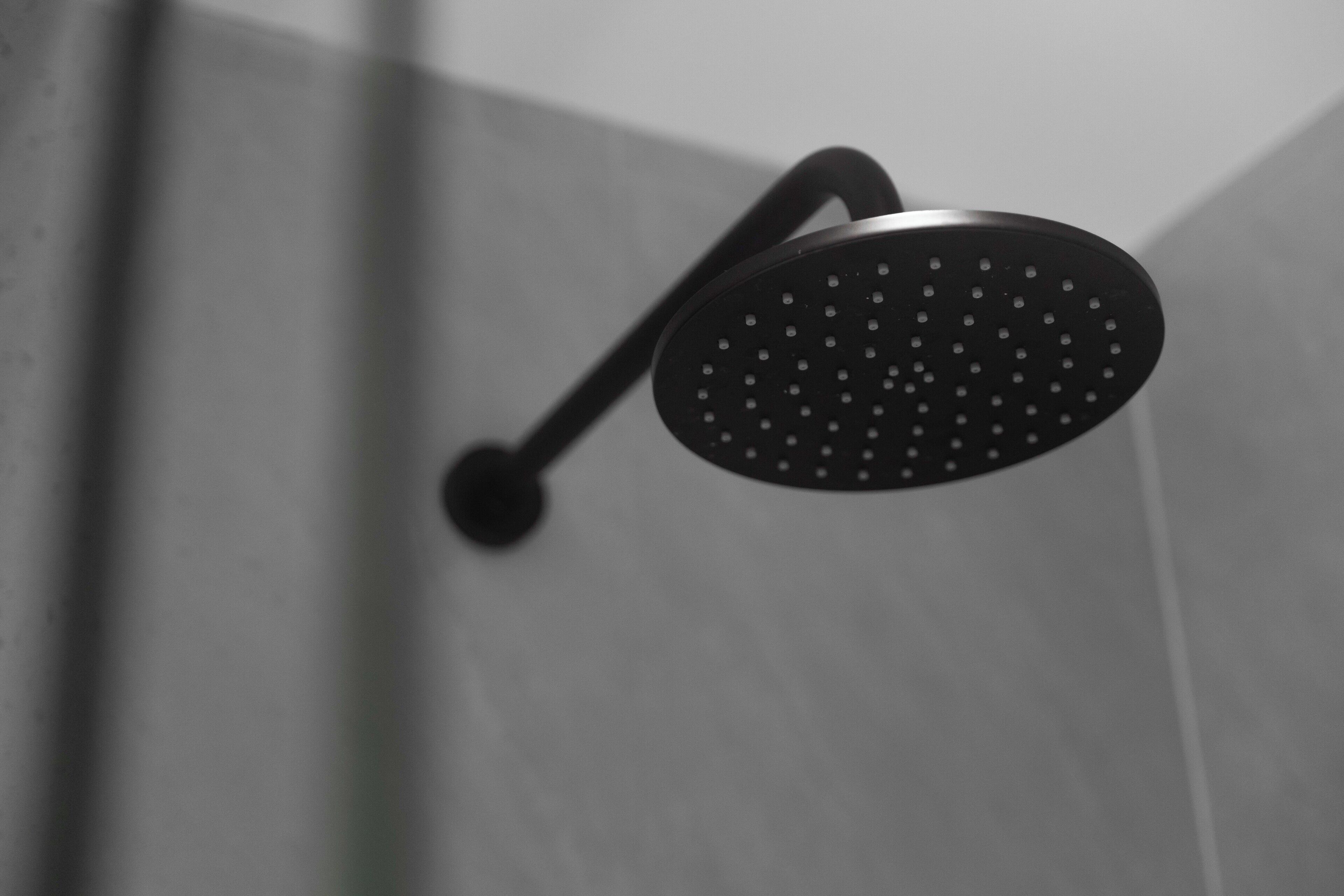 A modern showerhead with a curved design, mounted on a wall.
