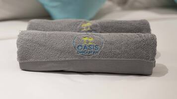 Two grey towels with a logo and text on a bed.