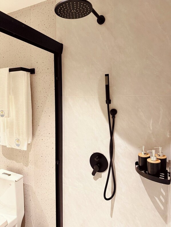Un baño moderno con ducha, toallero y dispensador de jabón.
