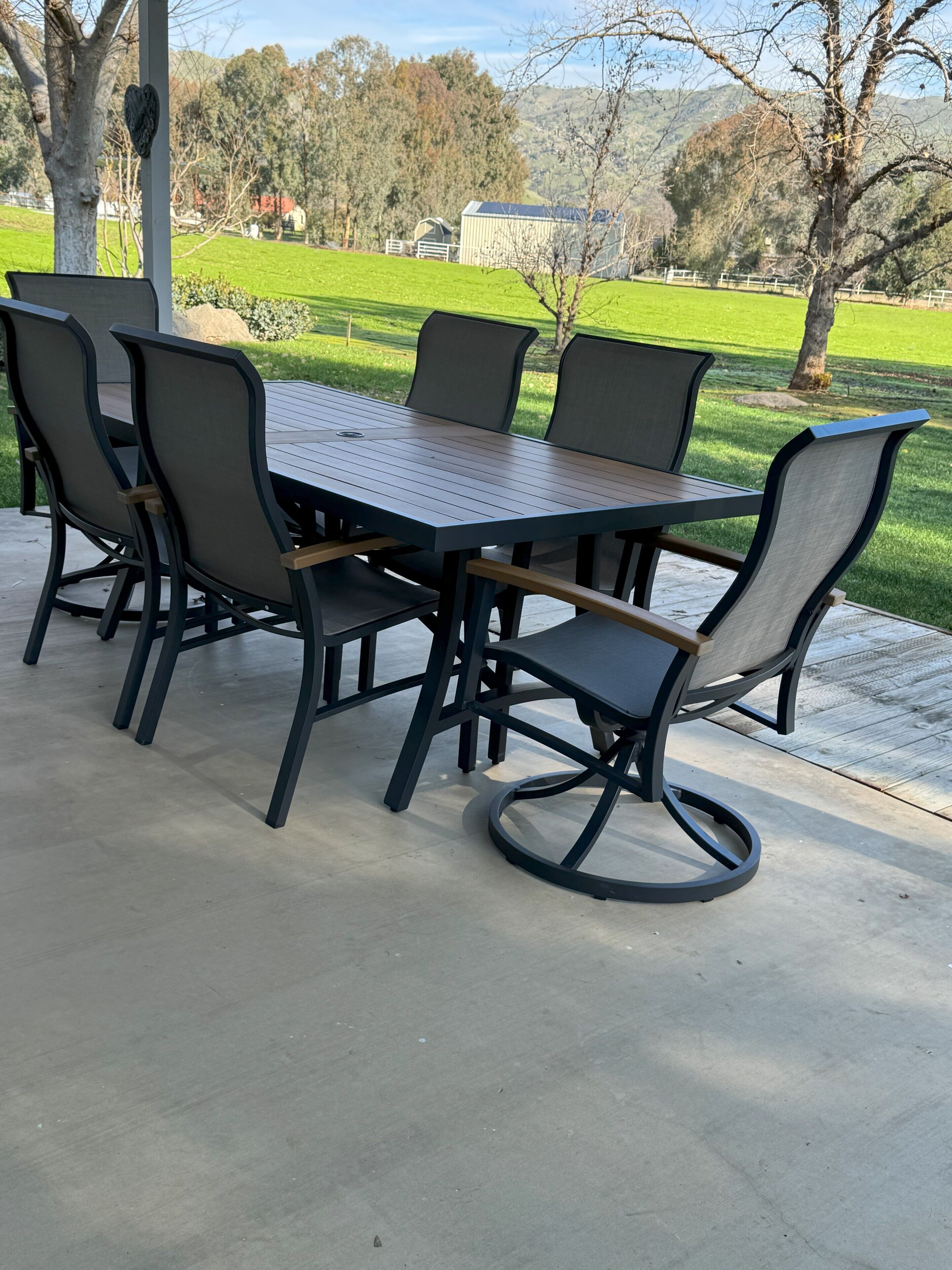 Eine Terrasse im Freien mit einem rechteckigen Tisch und sechs Stühlen.