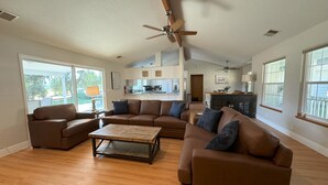 A spacious living room with a large brown sectional sofa, a wooden coffee table, and a ceiling fan.