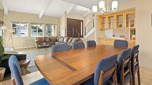 Een ruime eetruimte met een grote houten tafel en blauwe fauteuils.