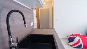A modern bathroom with a black sink, wooden wall paneling, and a view of a bedroom with a flag-patterned blanket. - 2 Rooms Air-conditioned near Cannes beaches (Le Cannet)