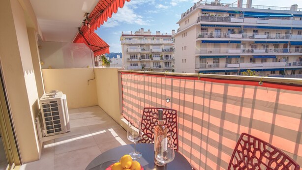 A balcony with a table, two chairs, a glass of water, and a plate of lemons. - 2 Rooms Air-conditioned near Cannes beaches (Le Cannet)