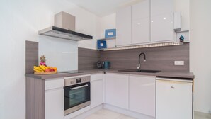 A modern kitchen with white cabinets, a built-in oven, a dishwasher, and a stainless steel sink. - 2 Rooms Air-conditioned near Cannes beaches (Le Cannet)
