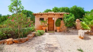 Un petit bâtiment en pierre, avec un toit en tuiles, une porte en bois et un chemin de gravier menant à l’entrée.