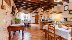 Une cuisine rustique avec des poutres apparentes, un mur en pierre et un coin repas doté de meubles en bois.