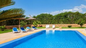 Une piscine avec des chaises longues et un mur en pierre.