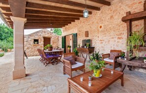 An outdoor patio with stone flooring, wooden furniture, and potted plants. - Country House 'Son Dalabau' with Private Pool, Wi-Fi and Air Conditioning (Illes Balears)