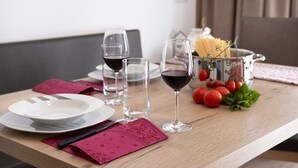 Een eettafel met borden, glazen en een pastabak.
