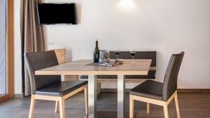 A dining area with a table, chairs, a bottle, glasses, and a magazine. - Apartment 'Hausergut Bonita 1' with Mountain View, Shared Garden and Wi-Fi (Sluderno)