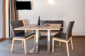 Un coin repas avec une table, des chaises, une bouteille, des verres et un magazine.